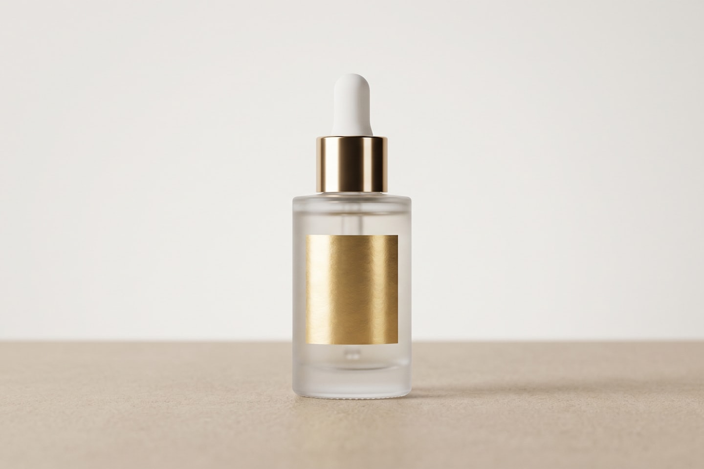 Frosted glass dropper bottle with golden collar on beige surface.