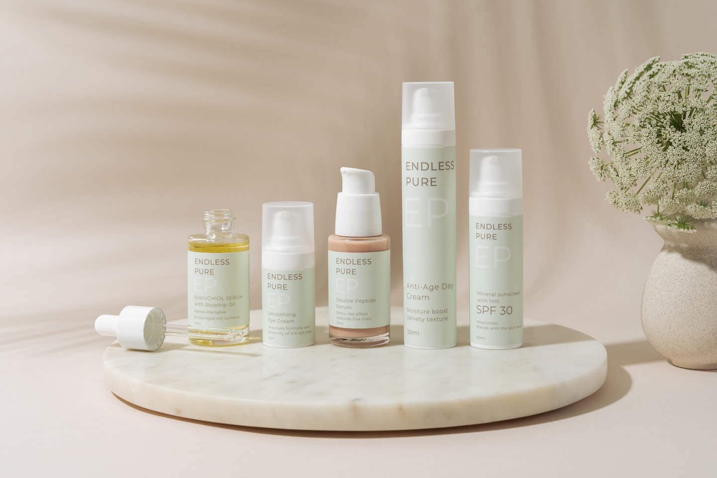 Skincare products arranged on a white marble tray with flowers.